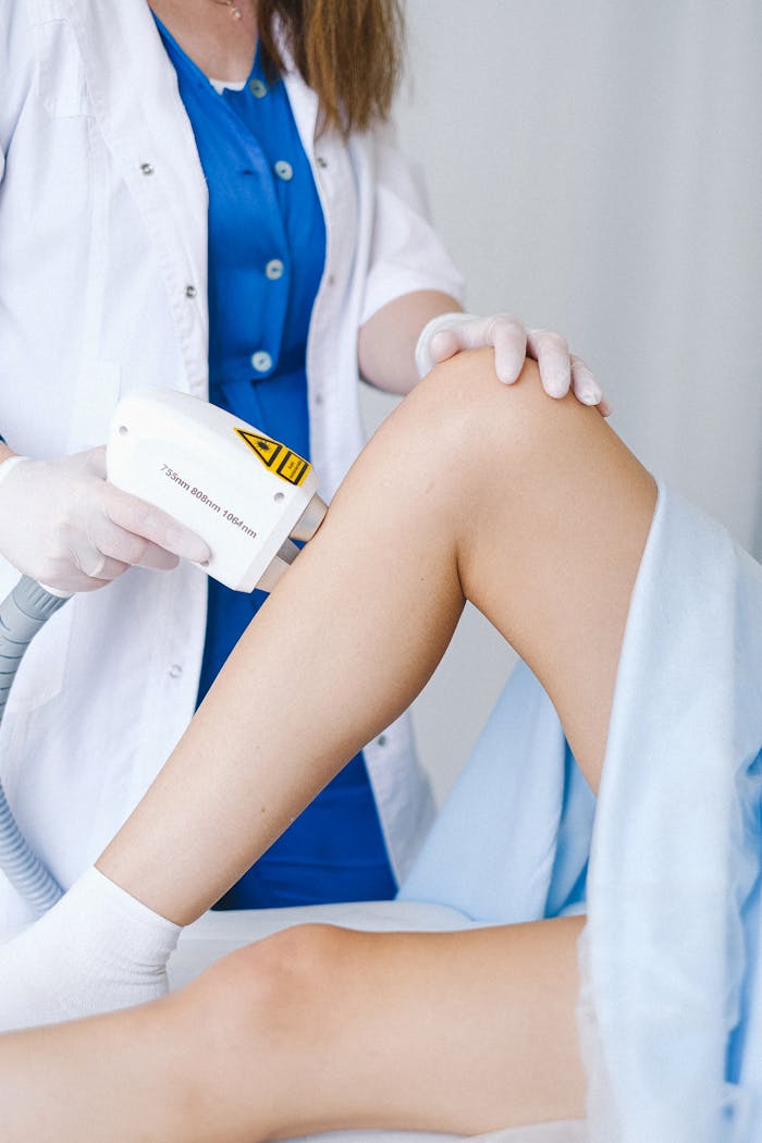 Services Crop unrecognizable doctor in medical uniform and gloves using professional equipment for low level laser therapy for client